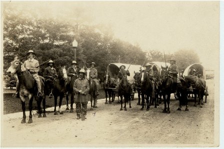 W26, men on horses holding rifles and wagons in back