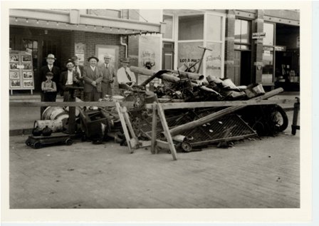 W43, six men and boy stand behind, towns cleanup rubble