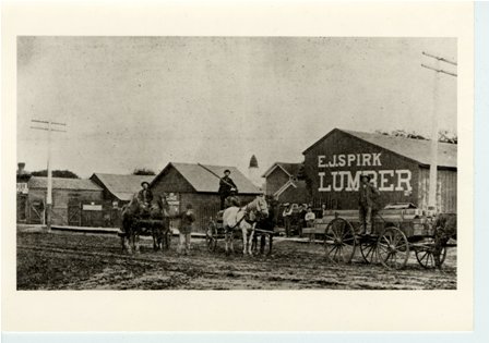 W60, 3 lumber wagons outside E. J. Spirk Lumber business